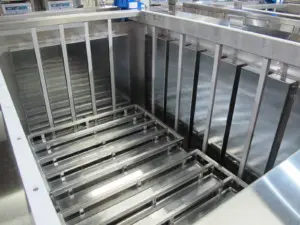 Stainless steel industrial ultrasonic cleaning tank interior with side-mounted transducers and submerged parts rack Stainless steel industrial ultrasonic cleaning tank interior with side-mounted transducers and submerged parts rack