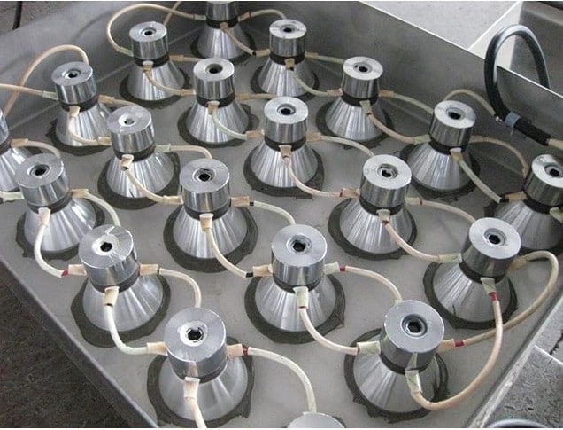 Tray of metal pipes displaying ultrasonic cleaning transducer types in Rockaway