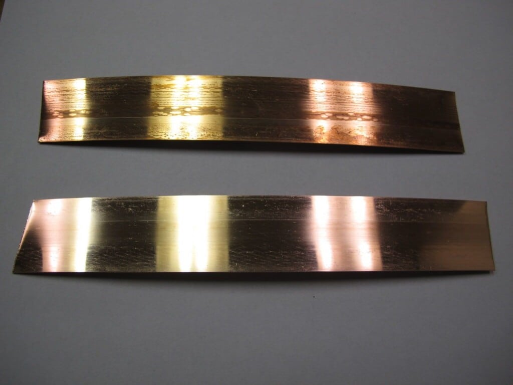 Two metal strips on a gray surface, showcasing Scale Remover 22, in Rockaway